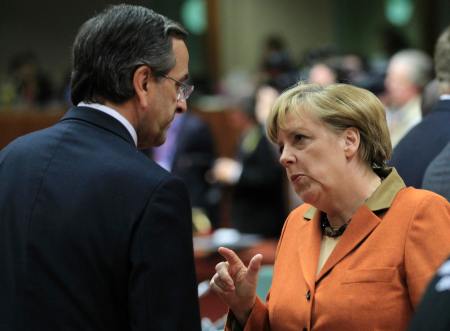 Greece's Prime Minister Antonis Samaras talks with Germany's Chancellor Angela Merkel during a European Union leaders summit at the European Council headquarters in Brussels