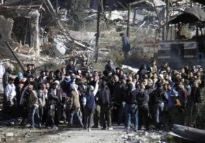 Civilians wait to be evacuated from a besieged area of Homs