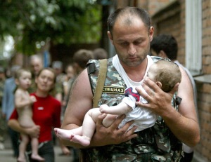 Russian police officer carries a released baby from the school seized by heavily armed masked men ...