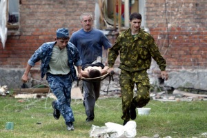 Volunteers carry an injured civilian to safety after soldiers stormed a school seized by heavily arm..