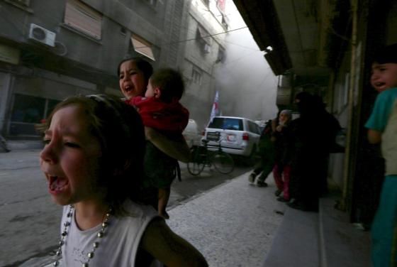 Ghazal, 4, (L) and Judy, 7, carrying 8-month-old Suhair, react after what activists said was shelling by forces loyal to Syria's President Bashar al-Assad near the Syrian Arab Red Crescent center in the Douma neighborhood of Damascus May 6, 2015. REUTERS/Bassam Khabieh